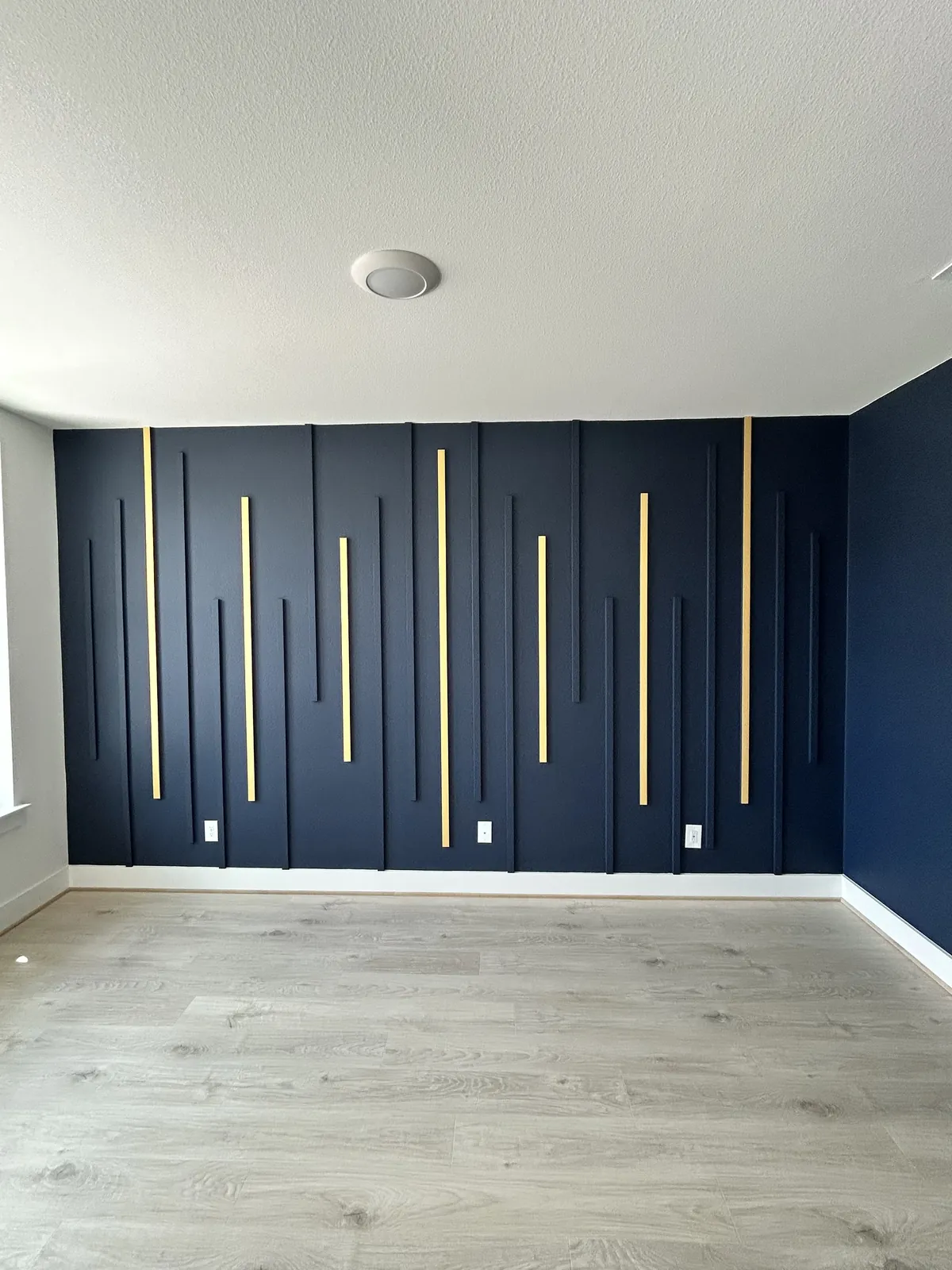 Navy board-and-batten accent wall with brass inlay strips.