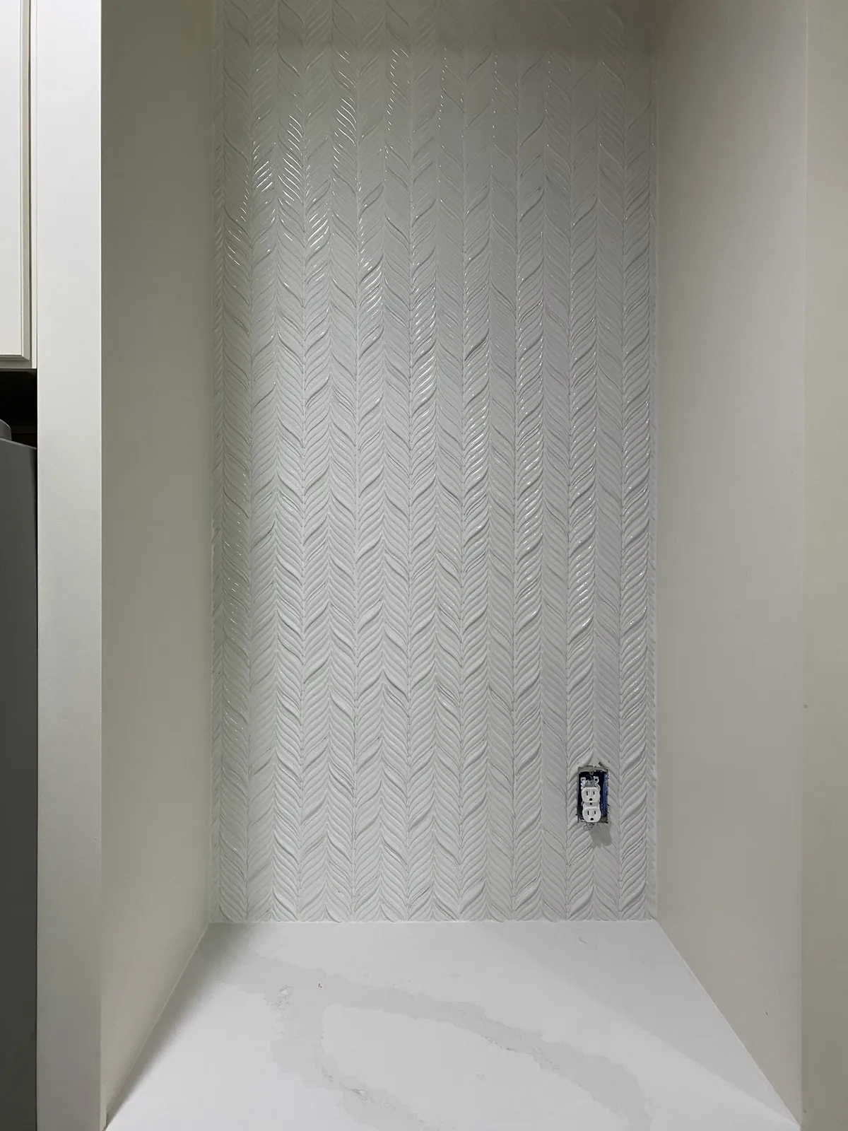 Herringbone tile feature wall in a white niche.