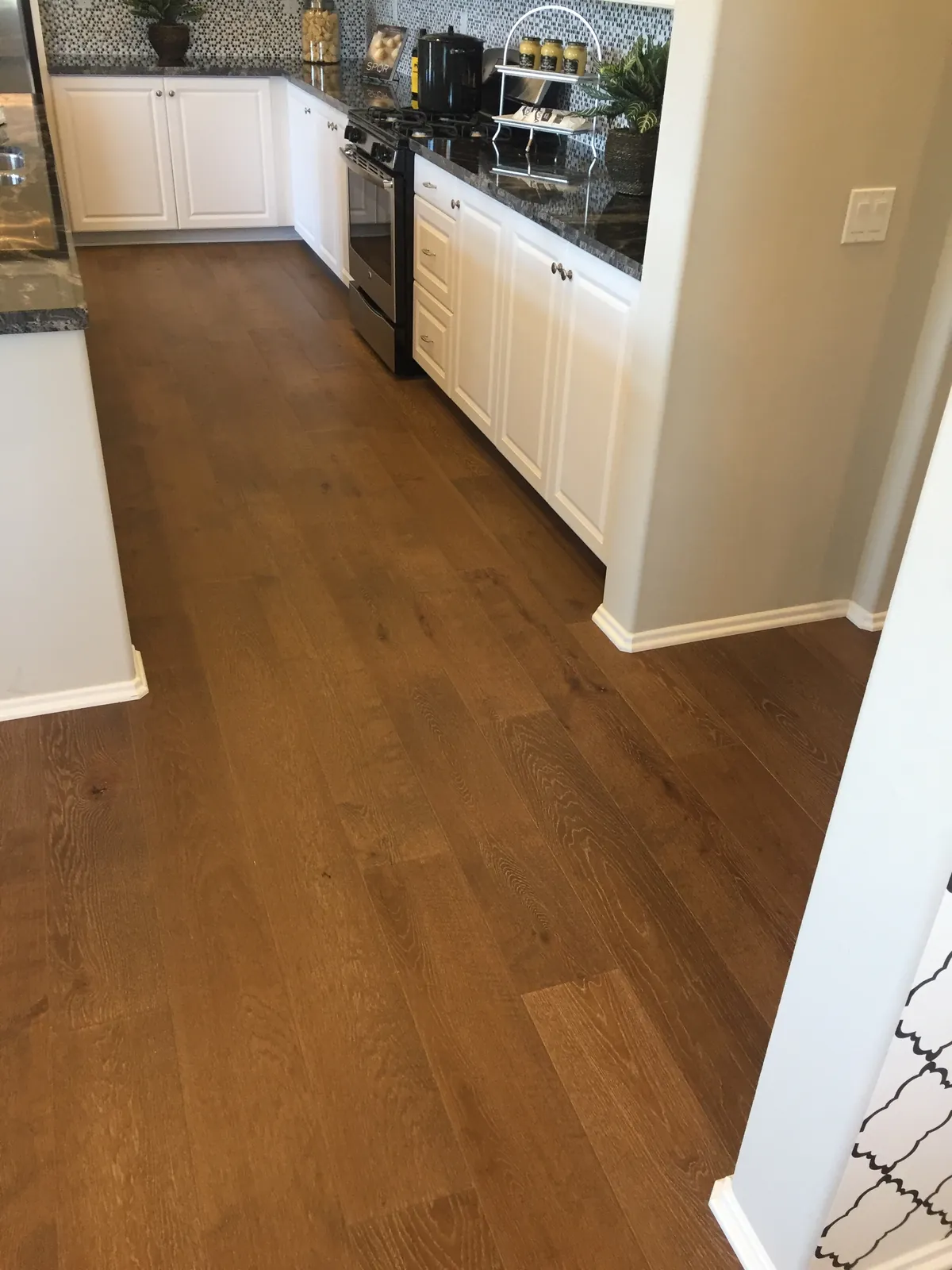 Black hutch kitchen with white cabinets and hardwood floor.